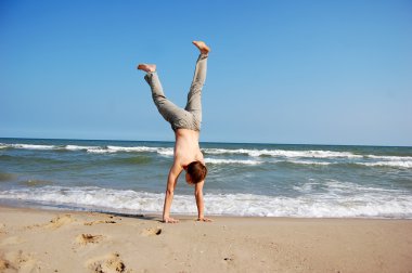 Acrobatic men on the beach. clipart