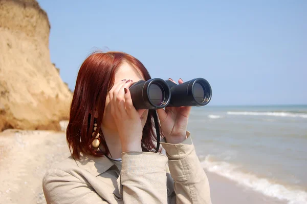 Flicka med kikare på stranden. — Stockfoto