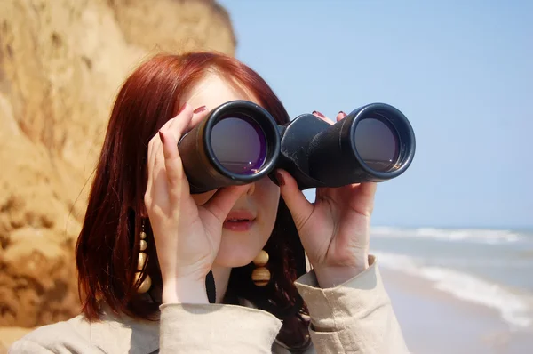 Flicka med kikare på stranden. — Stockfoto