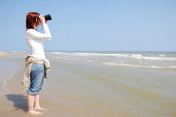 Meisje met verrekijker op strand. — Stockfoto