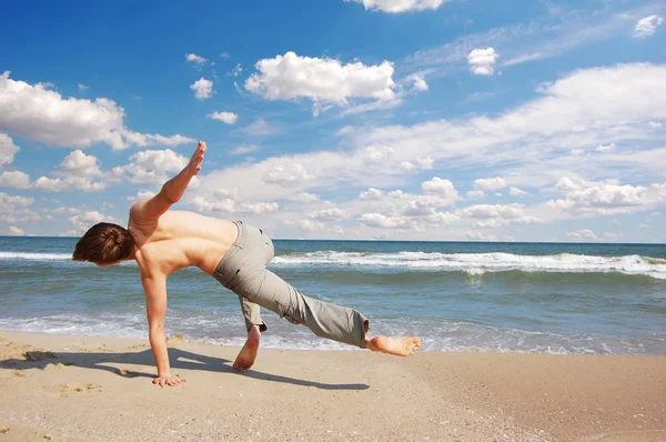 Akrobatiska pojke på stranden — Stockfoto