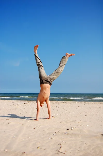 Akrobatyczny chłopak na plaży — Zdjęcie stockowe
