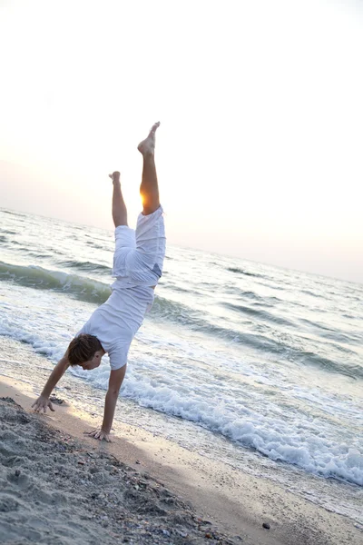 Young man doing cartwheels on the beach — Stock Photo, Image