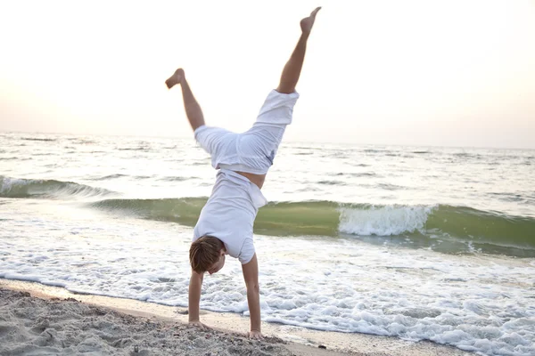 Młody człowiek robi cartwheels na plaży — Zdjęcie stockowe