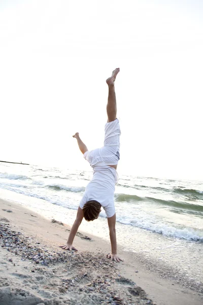 Ung man gör cartwheels på stranden — Stockfoto
