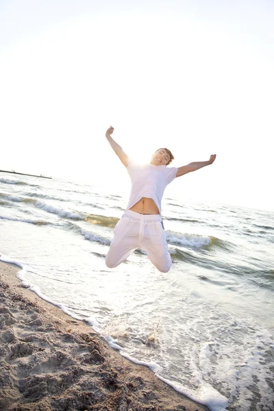 Jóvenes saltando a la playa al amanecer — Foto de Stock