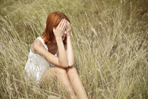 Ledsen rödhårig flicka på gräs. — Stockfoto