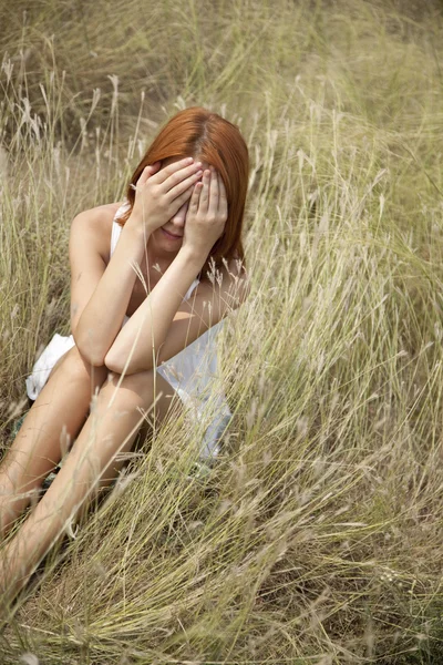 Ledsen rödhårig flicka på gräs. — Stockfoto
