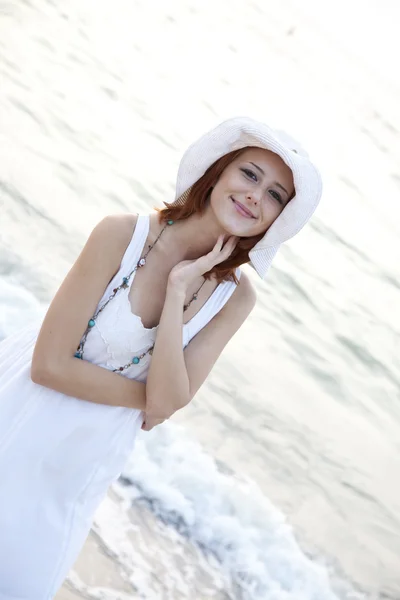 Mooie jonge roodharige meisje in de hoed op het strand — Stockfoto