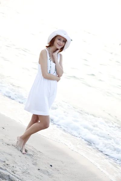 美丽年轻的红头发的女孩在海滩上的帽子 — 图库照片