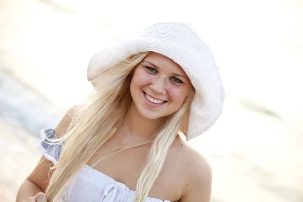 Mooie blonde meisje in de hoed op het strand — Stockfoto