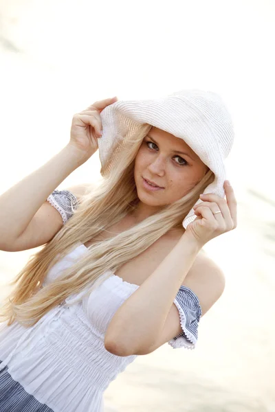 Όμορφη νεαρή κοπέλα ξανθιά με το καπέλο στην παραλία — Φωτογραφία Αρχείου