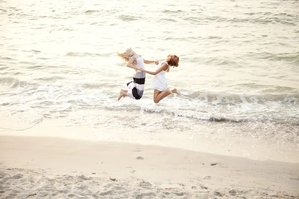 Duas belas jovens namoradas pulando na praia — Fotografia de Stock