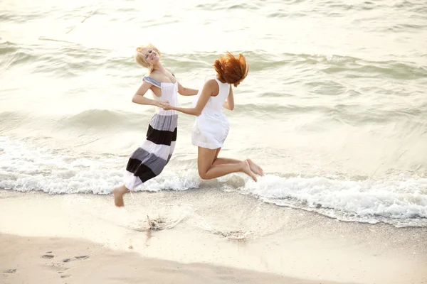 在海滩上跳跃的两个美丽年轻女友 — 图库照片