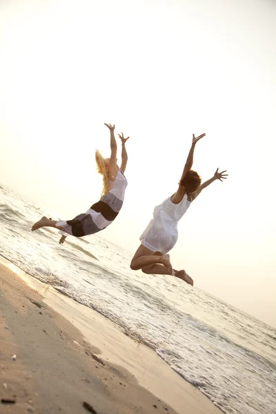 在海滩上跳跃的两个美丽年轻女友 — 图库照片