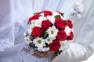 Bridegroom and bride holding beautiful red roses wedding flowers clipart