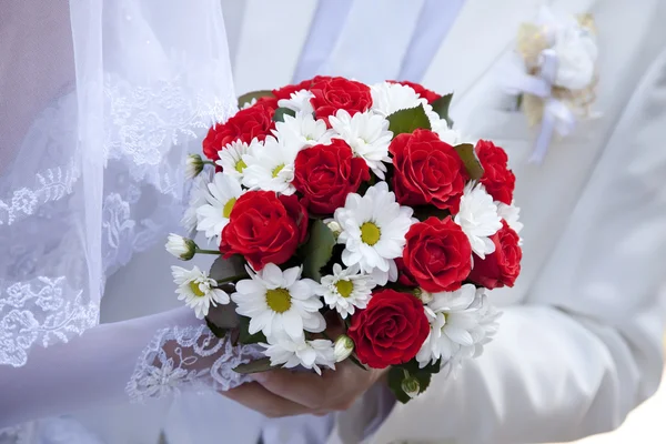Noivo e noiva segurando belas rosas vermelhas flores do casamento — Fotografia de Stock