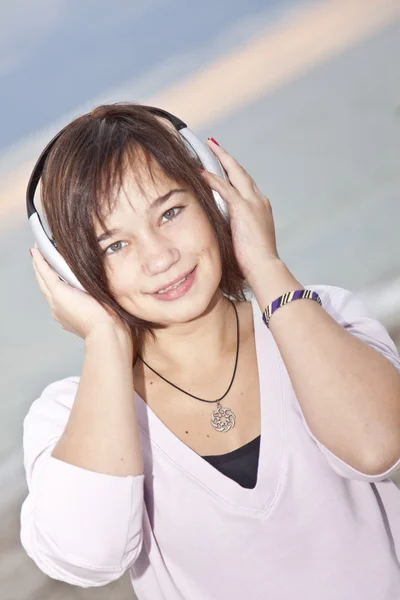Young brunet girl with headphones on the beach. — Stock Photo, Image