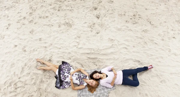 Dos hermosas chicas tumbadas en la arena . —  Fotos de Stock