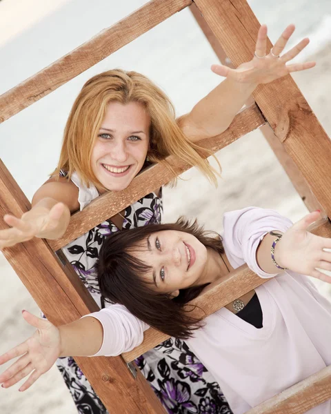 Retrato de duas meninas perto de escadas de madeira na praia . — Fotografia de Stock