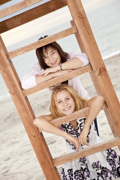 Portret van twee meisjes in de buurt van houten trappen op het strand. — Stockfoto