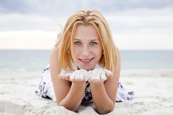 美丽的金发女孩躺在海滩上的沙子上在雨天. — 图库照片