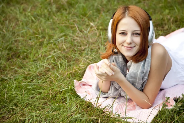 Chica de la moda joven con auriculares tumbados en la hierba verde —  Fotos de Stock