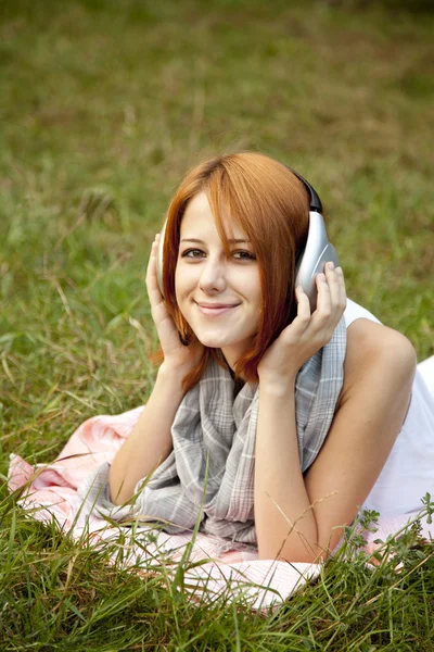 Junges Modemädchen mit Kopfhörer liegt im grünen Gras — Stockfoto
