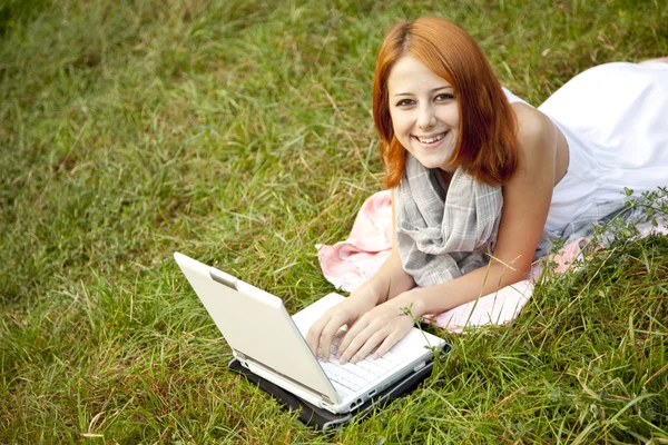 Giovane ragazza di moda con notebook sdraiato a erba verde — Foto Stock