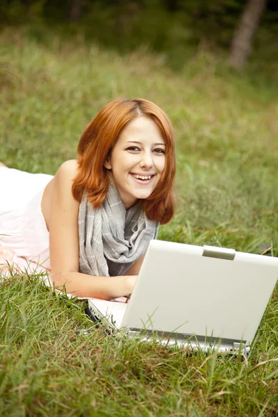 Jonge mode meisje met laptop liggen op groen gras — Stockfoto