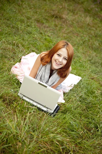 Menina de moda jovem com notebook deitado na grama verde — Fotografia de Stock