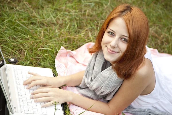 Moda młoda dziewczyna z notebooka leżącego na zielonej trawie — Zdjęcie stockowe