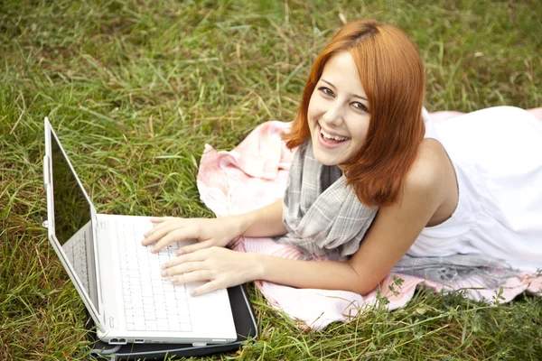 Menina de moda jovem com notebook deitado na grama verde — Fotografia de Stock