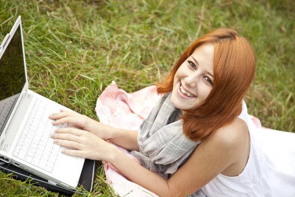 Jonge mode meisje met laptop liggen op groen gras — Stockfoto