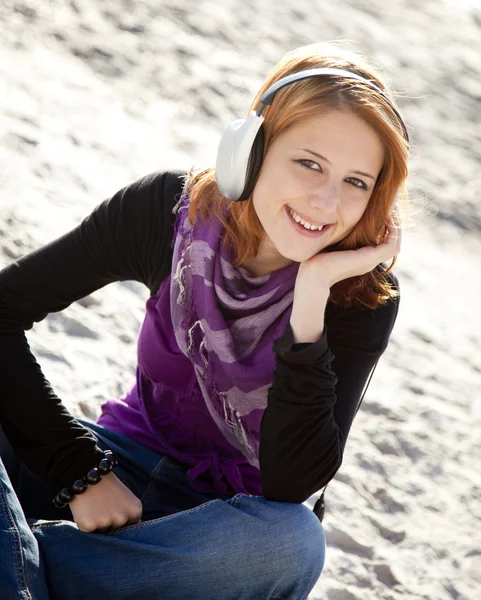 耳机在海滩上的红发女孩的肖像. — 图库照片