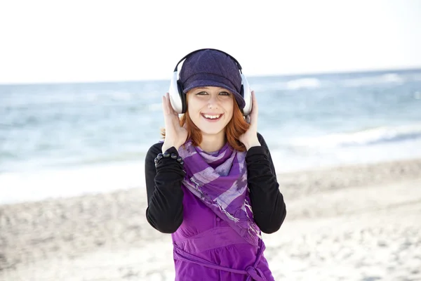 Πορτρέτο του κοκκινομάλλα κοπέλα με ακουστικά στην παραλία. — Φωτογραφία Αρχείου