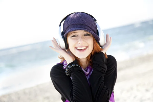 Retrato de chica pelirroja con auriculares en la playa . — Foto de Stock