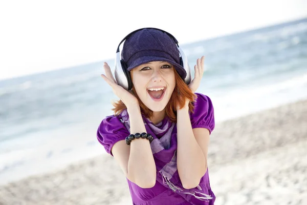 ビーチでヘッドフォンで赤い髪の少女の肖像画. — ストック写真
