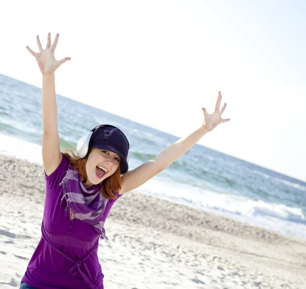 Portrét rusovlasá dívka s sluchátka na pláži. — Stock fotografie
