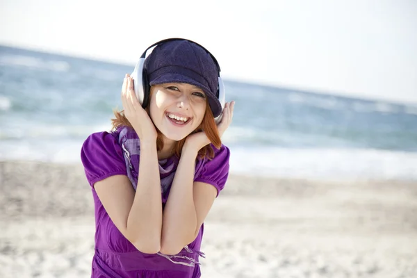 Kızıl saçlı kız sahilde kulaklık ile portresi. — Stok fotoğraf