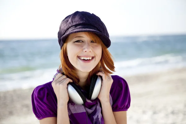 Portret van roodharige meisje met hoofdtelefoon op het strand. — Stockfoto