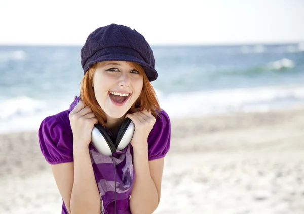 Portrét rusovlasá dívka s sluchátka na pláži. — Stock fotografie
