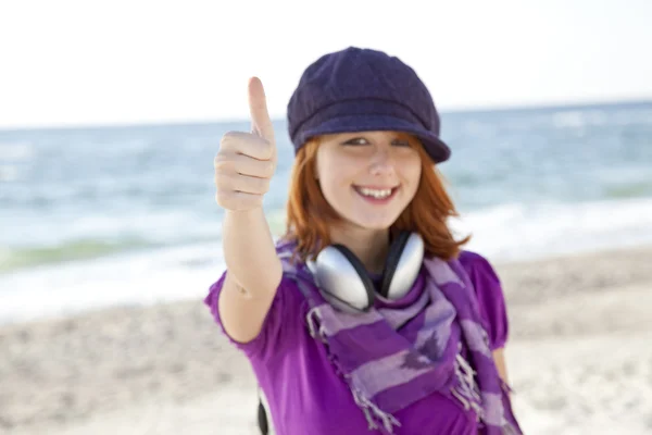 Roodharige meisje met hoofdtelefoon op het strand. — Stockfoto