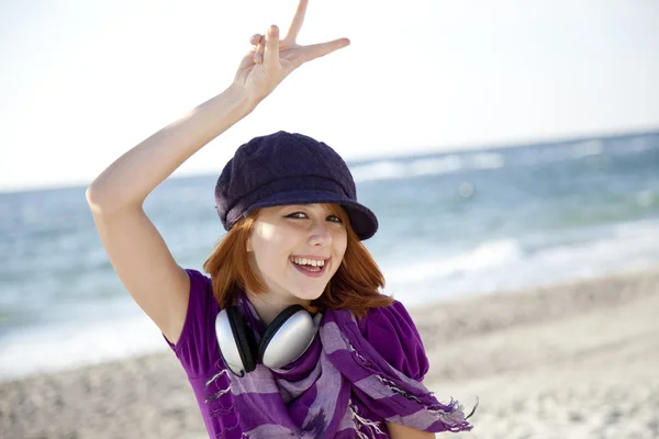 Menina de cabelos vermelhos com fone de ouvido na praia . — Fotografia de Stock