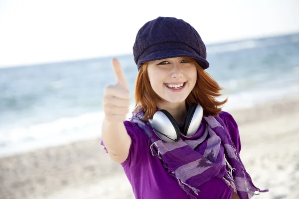Red-haired girl with headphone on the beach. — Stock Photo, Image