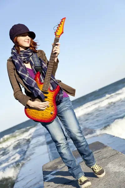 Young red-haired girl play on guitar at windy day. — Stock Photo, Image