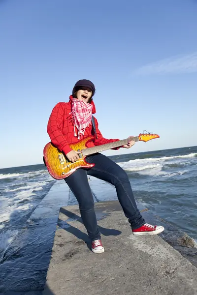 Fiatal brunet lány játszani a gitár a tengeri pier nap szél. — Stock Fotó