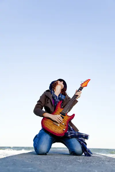年轻的红发女孩玩吉他上在刮风的日子. — 图库照片