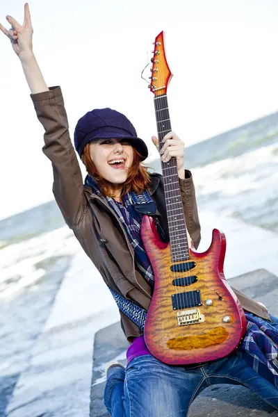 Ung rödhårig flicka spela gitarr på blåsig dag. — Stockfoto