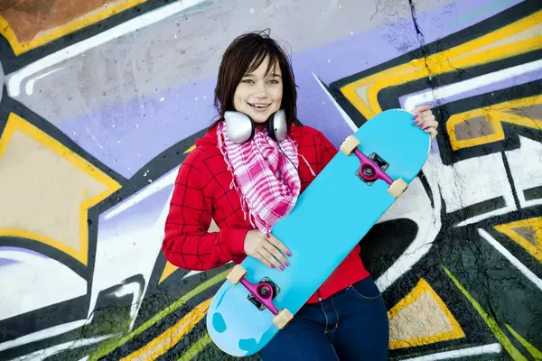 Closeup portrait of a happy young girl with skateboard and graff — Stock Photo, Image